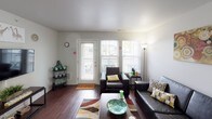 This single-floor unit features four bedrooms and two bathrooms within a practical and efficiently designed layout. The living room serves as the central gathering space, highlighted by rich hardwood-style flooring, large windows that invite natural light, and a welcoming front entry door. The open feel of the living area transitions naturally toward the kitchen and hallways leading to the bedrooms.

The kitchen is well-equipped with stainless steel appliances, including a refrigerator, range, and microwave. Dark gray cabinetry paired with granite-style countertops gives the kitchen a contemporary aesthetic, complemented by the warm wood-tone flooring.

Each of the four bedrooms features plush carpeting and individual windows that allow for natural light. Several bedrooms include mirrored sliding closet doors, offering both storage functionality and a sense of added space. The rooms are comfortably sized to accommodate standard bedroom furniture.

The two bathrooms are finished with hardwood-style flooring, single and double-sink vanities featuring wood cabinetry with granite-style countertops, and shower-tub combinations. The double-vanity bathroom provides added convenience for shared living arrangements.

Overall, the unit presents a clean, neutral palette throughout, making it a versatile and practical space well-suited for group or multi-occupant living.