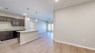 This well-appointed single-story home in Kyle, TX offers three bedrooms and four bathrooms within a thoughtfully designed open-concept floor plan. Light-toned wood-look flooring flows throughout the main living areas, complementing the neutral color palette and creating a clean, cohesive aesthetic.

The kitchen is a standout feature, showcasing rich dark espresso cabinetry, granite countertops, black appliances, and a large central island with pendant lighting overhead. Ample cabinet storage and recessed lighting make this an efficient and stylish culinary space that opens seamlessly into the living room.

The living room is bright and airy, benefiting from natural light through French doors that lead to an outdoor area. A ceiling fan adds comfort to the space, which flows naturally from the kitchen for easy entertaining.

The generously sized primary bedroom includes closet space and connects to a well-finished en-suite bathroom featuring dark wood vanity cabinetry, granite countertops, large-format tile flooring, and a glass-enclosed shower. Additional bedrooms are comfortably sized with access to similarly finished bathrooms that maintain design consistency throughout.

Each bathroom reflects the same attention to detail, with granite-topped dark vanities and clean tile finishes. The home's modern, neutral design and practical layout make it a functional and attractive residence in the growing Kyle, TX community.