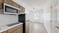 Located at 1023 Old Lascassas Rd in Murfreesboro, TN, this efficiently designed 2-bedroom, 1-bathroom unit offers a practical and modern living experience across a single floor. Light wood-style flooring runs throughout the space, creating a cohesive and clean aesthetic.

The kitchen is thoughtfully appointed with warm-toned cabinetry, white countertops, a stainless steel refrigerator, an over-the-range microwave, a smooth cooktop, and a single-basin sink — providing all essential cooking amenities in a compact, well-organized layout. The adjacent living area benefits from natural light streaming through a window and is topped with a ceiling fan for added comfort.

The primary bedroom is the larger of the two rooms, offering a comfortable footprint with a window that frames greenery outside, filling the space with natural light. The second bedroom mirrors the clean, simple design with its own window and bright white walls.

The bathroom features a full tub-shower combination with a curtain rod, a warm wood-toned vanity with a white countertop, and light wood-style flooring that ties seamlessly into the rest of the unit. The overall design is clean, modern, and functional, making this a well-suited space for those seeking straightforward, updated living in Murfreesboro.