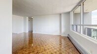 Located on a high floor at 15 Eva Road in Toronto's Etobicoke neighbourhood, this 2-bedroom, 1-bathroom unit offers a well-organized layout with distinct living spaces. Rich parquet hardwood flooring runs throughout the living areas and bedrooms, adding warmth and character to the interior. The open-concept living room is generously proportioned, bathed in natural light through large floor-to-ceiling windows that frame sweeping views of the Toronto skyline and surrounding greenery. A dedicated kitchen features dark espresso cabinetry, a mosaic tile backsplash, dark countertops, stainless steel appliances including a range, microwave, refrigerator, and dishwasher, along with a breakfast bar peninsula that connects the kitchen to the living area. The primary bedroom is spacious, with a large window showcasing elevated city views, while the second bedroom also benefits from natural light and a closet. The bathroom is finished with neutral large-format wall tiles surrounding a full soaker tub and shower combination, complemented by a mirror and clean white fixtures. A hallway connects the key areas of the unit efficiently. The crisp white walls throughout create a bright, neutral canvas well-suited for a variety of interior styles.