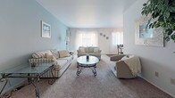 Located on Beech Road in Southfield, Michigan, this single-floor unit offers a well-organized and functional layout across several distinct living areas. The living room serves as the heart of the home, featuring soft carpeted flooring, a calming blue accent wall, and multiple windows dressed with vertical blinds that allow generous natural light to fill the space. The open and airy feel is complemented by a glass-top coffee table and comfortable seating arrangements.

Adjacent to the living room is a dedicated dining area with hardwood flooring, a ceiling fan, and a round glass-top dining table surrounded by elegant wrought-iron chairs — ideal for casual meals or entertaining.

The galley-style kitchen is efficiently designed with dark wood cabinetry lining both sides, white countertops, hardwood flooring, and standard appliances including a range, refrigerator, and dishwasher, with a convenient pass-through to additional living space.

The bedrooms are carpeted and well-lit, each offering closet storage. The primary bedroom features dual bi-fold closets and access to a walk-in shelving area, along with a ceiling fan. A secondary bedroom provides a bright window with natural light.

The full bathroom includes a combination tub and shower with glass sliding doors, dark wood vanity cabinetry, a white countertop, and classic mosaic tile flooring.