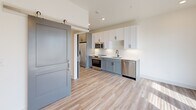 Located at 245 Beacon Town Dr in Huntersville, NC, this thoughtfully designed one-bedroom, one-bathroom residence offers a modern aesthetic with a clean, functional layout across a single floor. Light-toned luxury vinyl plank flooring flows throughout the entire unit, complementing the bright, neutral color palette that enhances the sense of openness.

The kitchen is a standout feature, equipped with a full suite of stainless steel appliances including a refrigerator, electric range, built-in microwave, and dishwasher. Two-toned cabinetry—white upper cabinets paired with slate-blue lower cabinets—adds visual interest, while white quartz countertops and a classic subway tile backsplash complete the polished look. A stylish sliding barn door separates the kitchen corridor from the main living area, adding a contemporary architectural detail.

The bedroom is a serene, well-proportioned space with a ceiling fan and direct access to the rest of the unit. A dedicated closet provides convenient storage. The bathroom features a gray vanity with quartz countertop, oil-rubbed bronze fixtures, a tiled tub/shower combination, and a stacked in-unit washer and dryer tucked neatly within the space. Recessed lighting throughout maintains a clean, modern ambiance.