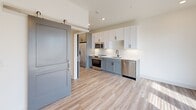 Located at 245 Beacon Town Dr in Huntersville, NC, this thoughtfully designed one-bedroom, one-bathroom residence offers a modern aesthetic with a clean, functional layout across a single floor. Light-toned luxury vinyl plank flooring flows throughout the entire unit, complementing the bright, neutral color palette that enhances the sense of openness.

The kitchen is a standout feature, equipped with a full suite of stainless steel appliances including a refrigerator, electric range, built-in microwave, and dishwasher. Two-toned cabinetry—white upper cabinets paired with slate-blue lower cabinets—adds visual interest, while white quartz countertops and a classic subway tile backsplash complete the polished look. A stylish sliding barn door separates the kitchen corridor from the main living area, adding a contemporary architectural detail.

The bedroom is a serene, well-proportioned space with a ceiling fan and direct access to the rest of the unit. A dedicated closet provides convenient storage. The bathroom features a gray vanity with quartz countertop, oil-rubbed bronze fixtures, a tiled tub/shower combination, and a stacked in-unit washer and dryer tucked neatly within the space. Recessed lighting throughout maintains a clean, modern ambiance.