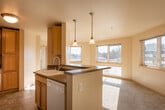 This single-floor unit is thoughtfully laid out to maximize functionality and comfort. The entryway opens to a view of the living area and kitchen, where natural light from multiple windows fills the space with a warm, inviting atmosphere. The flooring transitions from tile at the entry to plush carpet throughout the living and bedroom areas.

The kitchen is well-equipped with light maple cabinetry offering ample upper and lower storage, dark laminate countertops, and white Whirlpool appliances including a refrigerator, electric range, and over-the-range microwave. A peninsula with pendant lighting provides a casual dining or prep area and creates a natural division between the kitchen and living space.

The living area is generously sized with soft carpeting and windows that invite abundant natural light. The bedroom features plush carpet, a large closet with built-in wire shelving for organized storage, and direct access to the bathroom. The bathroom includes a single-sink vanity with a warm laminate countertop, a large mirror, tile flooring, and a full-size soaking tub with a tiled surround. The unit's neutral color palette and clean finishes create a cohesive, move-in-ready environment.