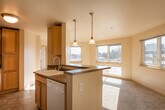 This single-floor unit is thoughtfully laid out to maximize functionality and comfort. The entryway opens to a view of the living area and kitchen, where natural light from multiple windows fills the space with a warm, inviting atmosphere. The flooring transitions from tile at the entry to plush carpet throughout the living and bedroom areas.

The kitchen is well-equipped with light maple cabinetry offering ample upper and lower storage, dark laminate countertops, and white Whirlpool appliances including a refrigerator, electric range, and over-the-range microwave. A peninsula with pendant lighting provides a casual dining or prep area and creates a natural division between the kitchen and living space.

The living area is generously sized with soft carpeting and windows that invite abundant natural light. The bedroom features plush carpet, a large closet with built-in wire shelving for organized storage, and direct access to the bathroom. The bathroom includes a single-sink vanity with a warm laminate countertop, a large mirror, tile flooring, and a full-size soaking tub with a tiled surround. The unit's neutral color palette and clean finishes create a cohesive, move-in-ready environment.