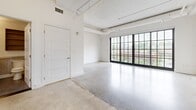 Located at 675 Ponce de Leon Ave NE in Atlanta's vibrant Old Fourth Ward, this loft-style unit on the fourth floor of the iconic Ponce City Market building showcases a thoughtfully designed open-concept layout with a strong industrial character. Polished concrete floors extend throughout the main living area, complemented by soaring ceilings with exposed ductwork, structural beams, and hanging pendant lighting that pays homage to the building's historic warehouse origins. A wall of large, multi-pane factory-style windows floods the main living space with abundant natural light and offers elevated views of the surrounding Atlanta skyline and neighborhood. The kitchen is well-appointed with wood-grain cabinetry, white subway tile backsplash, light countertops, a stainless steel gas range, and a full-size stainless steel refrigerator. A dedicated closet provides practical storage, while the bathroom features subway-tiled walls, a soaking tub with an overhead rainfall shower, brushed steel grab bars, a modern vanity with an undermount sink, and dark tile flooring. The seamless integration of industrial aesthetics with contemporary finishes gives this space a distinctive and functional character throughout.