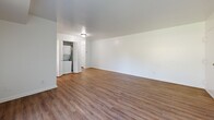 Located at 8501 Walther Blvd in Nottingham, MD, this single-floor, 2-bedroom unit offers a practical and comfortable layout across a well-utilized floor plan. The living area is a bright, open space featuring warm wood-look laminate flooring and a large sliding glass door dressed with vertical blinds, allowing abundant natural light and outdoor views. A dedicated hallway with wood-look flooring connects the main living spaces and includes a stacked washer and dryer unit, adding everyday convenience. The kitchen is thoughtfully designed with crisp white cabinetry, light quartz-style countertops, a stainless steel sink with a matte black faucet, and stainless steel appliances including an electric range and over-the-range microwave. A window above the counter brings in natural light, enhancing the clean, modern aesthetic. Both bedrooms feature soft, neutral carpeting and windows with blinds that provide natural light. The primary bedroom offers a generous footprint with a built-in closet, while the second bedroom also includes closet storage and a bright window. White panel doors with matte black hardware are consistent throughout, lending a cohesive, updated look. The overall ambiance is clean, neutral, and move-in ready.