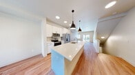 Located at 4924 Dunham Dr in Olympia, WA, this three-story home offers a well-organized layout distributed across three distinct levels. The entry level provides a compact transitional space leading to the main living areas, connected by wood-tread staircases with white railings that flow cleanly between floors.

The main level serves as the social hub of the home, centered around an open-concept kitchen and living area. The kitchen is equipped with stainless steel appliances, including a French door refrigerator, electric range, and microwave. Tall white cabinetry lines the walls, complemented by a lengthy island featuring a undermount sink and white quartz countertops. Matte black pendant lights hang above the island, adding a modern contrast. Light hardwood flooring extends throughout, and a sliding glass door at the far end brings in natural light.

The upper level houses all three bedrooms and two bathrooms. The primary bedroom features vaulted ceilings, a ceiling fan, and a window with natural light. Its ensuite bathroom includes a double-sink vanity with white cabinetry and a large mirror. The secondary bathroom offers a full tub-shower combination with white surrounds and a single-sink vanity. Additional bedrooms are well-proportioned with hardwood floors and ceiling fans.
