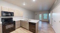 Located at 2008 Runestone Ave in Alexandria, Minnesota, this one-bedroom, one-bathroom unit offers a thoughtfully designed layout with modern finishes throughout. The open-concept kitchen is a standout feature, equipped with black appliances including a refrigerator, range, and over-the-range microwave, complemented by light wood cabinetry, white countertops, and a peninsula with a sink — ideal for both cooking and casual dining. Light wood-tone flooring flows through the main living and kitchen areas, creating a bright and cohesive feel. The bedroom is a comfortable, carpeted retreat featuring a large window that brings in natural light and a baseboard heating system. A dedicated walk-in closet off the bedroom provides generous storage with built-in wire shelving on multiple levels. The bathroom is finished with a wide vanity, light wood cabinetry, a large mirror, and light wood-tone flooring. The building exterior features contemporary board-and-batten siding, landscaped green areas, and private balconies on upper levels. This well-appointed unit combines functional design with clean, modern aesthetics in a residential Alexandria setting.
