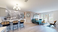 Located at 350 Fieldpointe Blvd in Frederick, Maryland, this well-appointed single-floor home offers a thoughtfully designed open-concept layout that seamlessly connects the main living areas. The kitchen is a standout feature, equipped with stainless steel appliances, gray shaker-style cabinetry, white countertops, a subway tile backsplash, and a spacious peninsula with seating for four — all illuminated by a modern chandelier and easy-care light wood-style flooring that flows throughout the common areas. The open living and dining area extends naturally from the kitchen, anchored by a fireplace and a wall of French doors that flood the space with natural light and provide direct access to the outdoors. The bedrooms are generously sized with plush carpeting; the primary suite features a bold teal accent wall, ample natural light from a bright window, and a walk-in closet with direct access to a private bathroom. Additional bedrooms offer a calm, neutral palette with garden views. The home's cohesive design blends modern finishes with inviting warmth throughout, making it a comfortable and functional living space in a well-situated Frederick neighborhood.