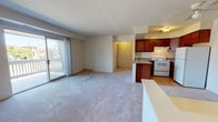 This single-floor unit in Woodhaven, Michigan, offers a practical and well-organized layout designed to maximize usable space. The open-concept living and dining area is finished with plush neutral carpeting and is anchored by a ceiling fan overhead, creating a comfortable, airy atmosphere. A sliding glass door leads to a private balcony, allowing natural light to fill the space while providing outdoor views.

The kitchen is positioned adjacent to the living area and is separated by a peninsula countertop that serves as a convenient breakfast bar. Rich medium-toned wood cabinetry lines the walls, complemented by granite-style countertops. White appliances, including a refrigerator, electric range, and under-cabinet range hood, are included, and the kitchen is finished with light hardwood-style flooring.

The bedroom is generously proportioned, featuring soft carpeting, a window with outdoor views, a dedicated closet, and direct access to the full bathroom. The bathroom is outfitted with a granite-topped vanity featuring rich wood cabinetry, a large mirror, tiled flooring, and a shower-tub combination, delivering a clean and functional finish throughout.