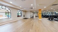 Located at 300 N Beaudry Ave in Los Angeles, CA, this fitness center offers a generously sized, single-floor exercise facility thoughtfully designed to accommodate a wide range of workout needs. The space is divided into distinct functional zones, each equipped to support various training styles.

The strength training area features bold orange accent columns, floor-to-ceiling mirrors that amplify the sense of space, and light hardwood flooring throughout. This zone is outfitted with a full rack of dumbbells, multiple cable and resistance machines, free-motion equipment, and functional training rigs including an Atlas cable system and kettlebells, providing comprehensive options for strength and resistance work.

The cardio zone houses a row of True-brand treadmills, StairMaster step mills, and a rowing machine, all positioned alongside wall-spanning mirrors and recessed lighting that creates a bright, energizing atmosphere. An open stretch and movement area with clean, neutral walls and arched windows allows natural light to filter in, lending a calm, airy quality to the space. Retail beverage displays and clearly posted fitness center rules round out the amenities. The layout flows seamlessly between zones, making this a well-organized and fully equipped facility for residents and guests.