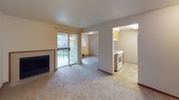 This single-floor unit offers a practical and comfortable layout across several well-defined spaces. The living room serves as the central gathering area, highlighted by a tiled fireplace surround and a sliding glass door that opens to a private balcony, offering views of mature, flowering trees and greenery. Warm neutral carpet extends throughout the living and bedroom areas, contributing to a cohesive, understated aesthetic.

The kitchen is efficiently designed with medium-toned wood cabinetry, a peninsula with a built-in cooktop, and tile flooring in a natural stone pattern. White appliances including a range and refrigerator provide a clean, functional workspace, while a sink overlooks the surrounding cabinetry. Adjacent open space allows for comfortable traffic flow between the kitchen and living areas.

The bedrooms are carpeted and feature baseboard heating, windows fitted with vertical blinds for light control, and wood-toned sliding closet doors for ample storage. The full bathroom includes a vanity with wood cabinetry, a tub-shower combination, and matching tile flooring that mirrors the kitchen, tying the unit together with a consistent design language throughout.