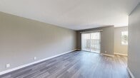 Located at 1125 N Broadway in Escondido, CA, this single-floor unit offers five bedrooms, one bathroom, and a well-organized layout across a comfortable footprint. The combined living and dining area serves as the heart of the home, featuring sleek wood-look laminate flooring in a cool gray tone and neutral taupe walls that create a clean, modern aesthetic. A full-width sliding glass door fitted with vertical blinds floods the living room with natural light and provides outdoor access. The dining area includes a window overlooking a landscaped courtyard, accented by pendant lighting above.

The galley-style kitchen is efficiently designed with white cabinetry, matte black hardware, light quartz-style countertops, a double basin sink, and white appliances including a gas range and refrigerator — all set over warm wood-look flooring.

The five bedrooms feature plush carpeting, neutral gray walls, and textured ceilings. Several rooms include built-in closets, and the primary bedroom is a comfortable size with a ceiling fan and natural light from a window with vertical blinds. Two hallways connect the bedrooms, a closet, and the shared bathroom, which includes a full tub/shower combo, toilet, and vanity with warm-toned countertop.