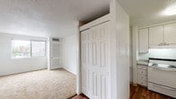 Located in the vibrant Midtown neighborhood of Nashville, TN, this single-floor unit at 1906 Adelicia St offers a practical and comfortable layout with a clean, neutral aesthetic throughout. The living area features a seamless transition between rich hardwood-style flooring and plush wall-to-wall carpeting, creating distinct zones within an open feel. Bright white walls and a ceiling fan complement the entry area, which flows naturally into the main living space. A wide window in the carpeted bedroom area frames elevated views of the Nashville skyline and surrounding cityscape, filling the room with natural light. The kitchen is efficiently laid out with white cabinetry, a white range, and ample counter space, designed for everyday functionality. Storage is well-addressed throughout, with closet doors visible in multiple areas of the unit. The bathroom features a wide vanity with a speckled countertop, an undermount sink with brushed gold fixtures, white cabinetry below, and a large mirror. Textured ceilings are present in portions of the unit, adding a classic touch. Overall, this unit offers a straightforward, move-in-ready layout well-suited for urban living in one of Nashville's most centrally located neighborhoods.
