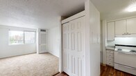Located in the vibrant Midtown neighborhood of Nashville, TN, this single-floor unit at 1906 Adelicia St offers a practical and comfortable layout with a clean, neutral aesthetic throughout. The living area features a seamless transition between rich hardwood-style flooring and plush wall-to-wall carpeting, creating distinct zones within an open feel. Bright white walls and a ceiling fan complement the entry area, which flows naturally into the main living space. A wide window in the carpeted bedroom area frames elevated views of the Nashville skyline and surrounding cityscape, filling the room with natural light. The kitchen is efficiently laid out with white cabinetry, a white range, and ample counter space, designed for everyday functionality. Storage is well-addressed throughout, with closet doors visible in multiple areas of the unit. The bathroom features a wide vanity with a speckled countertop, an undermount sink with brushed gold fixtures, white cabinetry below, and a large mirror. Textured ceilings are present in portions of the unit, adding a classic touch. Overall, this unit offers a straightforward, move-in-ready layout well-suited for urban living in one of Nashville's most centrally located neighborhoods.