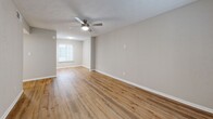 Located at 8601 Roberts Dr in Sandy Springs, GA, this 2-bedroom, 2-bathroom single-floor residence offers a well-organized and comfortable layout. The open living and dining area is bright and welcoming, featuring warm wood-look flooring, neutral-toned walls, and a ceiling fan that runs throughout the main living spaces. A sliding glass door with vertical blinds connects the living area to an outdoor space, allowing natural light to pour in. The kitchen is a standout feature, boasting granite countertops, white cabinetry, a classic subway tile backsplash, and a full suite of stainless steel appliances including a refrigerator, range, and built-in microwave, all accessible via a convenient breakfast bar. Both bedrooms are generously sized, each equipped with ceiling fans and ample closet access — multiple closets are distributed throughout the unit for excellent storage. The primary bedroom offers a spacious feel with room for a full furniture arrangement. Both bathrooms are finished with granite-topped white vanities, wood-look flooring, and tub-shower combinations with curved curtain rods. A dedicated laundry area and utility room round out the practical amenities of this thoughtfully designed home.