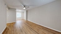 Located at 8601 Roberts Dr in Sandy Springs, GA, this 2-bedroom, 2-bathroom single-floor residence offers a well-organized and comfortable layout. The open living and dining area is bright and welcoming, featuring warm wood-look flooring, neutral-toned walls, and a ceiling fan that runs throughout the main living spaces. A sliding glass door with vertical blinds connects the living area to an outdoor space, allowing natural light to pour in. The kitchen is a standout feature, boasting granite countertops, white cabinetry, a classic subway tile backsplash, and a full suite of stainless steel appliances including a refrigerator, range, and built-in microwave, all accessible via a convenient breakfast bar. Both bedrooms are generously sized, each equipped with ceiling fans and ample closet access — multiple closets are distributed throughout the unit for excellent storage. The primary bedroom offers a spacious feel with room for a full furniture arrangement. Both bathrooms are finished with granite-topped white vanities, wood-look flooring, and tub-shower combinations with curved curtain rods. A dedicated laundry area and utility room round out the practical amenities of this thoughtfully designed home.