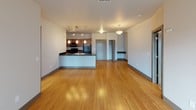 Located at 500 E Michigan Ave. in Lansing's Stadium District, this single-floor residence combines modern design with functional living. The open-concept living and dining area is anchored by warm bamboo hardwood flooring that flows seamlessly throughout the main space. A pendant-lit kitchen island with dark granite countertops serves as a natural focal point, complemented by rich cherry wood cabinetry, black stainless appliances including a refrigerator, range, and built-in microwave, and a track lighting system overhead. A sliding glass door in the living area provides access to an outdoor space and fills the room with natural light.

The bedrooms are carpeted and generously sized, each featuring multiple windows with blinds that invite ample natural light and views of the surrounding neighborhood. The primary bathroom includes a full tub-shower combination, a large vanity mirror with overhead lighting, and a warm wood vanity with a solid-surface countertop. A second half-bath offers a matching vanity and tile flooring, providing added convenience. The unit's neutral color palette and clean architectural lines create a polished, move-in-ready atmosphere throughout.