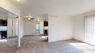 This single-floor residence offers a functional and well-organized layout designed for comfortable everyday living. The open living area is finished with neutral-toned carpet and bright white walls, creating a clean and airy atmosphere. A ceiling fan provides additional comfort, while large sliding glass doors flood the space with natural light and offer views of the surrounding greenery outside. The living area flows seamlessly toward the kitchen, which is laid out in a galley configuration. The kitchen features dark espresso-toned cabinetry, stainless steel appliances including a refrigerator and range, light countertops, and wood-look luxury vinyl plank flooring. A window above the kitchen allows natural light to brighten the workspace. The unit includes two carpeted bedrooms, each with windows dressed in vertical blinds that provide outdoor views and natural light. The primary bedroom is equipped with a ceiling fan and a full mirrored closet that adds a sense of depth and space. The second bedroom is well-proportioned and similarly bright. The bathroom features wood-look vinyl plank flooring, a dark vanity with a light countertop, and a full soaking tub with a classic tile surround in warm neutral tones. A window in the bathroom provides ventilation and additional light, completing this well-appointed residential space.