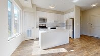 This 1-bedroom, 1-bathroom unit in California offers a thoughtfully designed single-floor layout that maximizes every square foot of its compact footprint. The entrance opens into a bright, open-concept living and kitchen area finished with warm-toned hardwood-style flooring and neutral walls throughout. Large sliding glass doors in the living room flood the space with natural light and provide direct access to a private balcony with views of the surrounding neighborhood.

The kitchen is well-equipped with crisp white cabinetry extending to the ceiling for ample storage, a light stone countertop, a peninsula island ideal for casual dining or meal prep, and a full suite of stainless steel appliances including a refrigerator, range, microwave, and dishwasher.

The spacious primary bedroom features a tray ceiling detail, a large closet with sliding panel doors, and a window that brings in additional natural light. An additional closet provides further storage convenience. The bathroom is clean and functional, appointed with a full soaking tub and shower combination with white tile surround. The unit also includes a dedicated entrance area with built-in storage, completing a practical and comfortable living space.