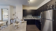 Located on Marathon Ave in Richardson, TX, this single-story residence offers a thoughtfully designed layout with modern finishes throughout. The kitchen is a standout feature, showcasing dark espresso cabinetry, granite countertops, a subway tile backsplash, and a full suite of stainless steel appliances including a refrigerator, built-in microwave, and range. Rich wood-look flooring anchors the kitchen, while a breakfast bar provides additional counter space and casual seating. The bedrooms are bright and welcoming, with plush carpet flooring, ceiling fans, and large windows dressed with blinds that invite natural light and offer views of the surrounding greenery. Generous closet space is a defining feature, including a spacious walk-in closet with multi-level wire shelving for efficient organization. The bathroom is well-equipped with a granite-topped vanity, dark cabinetry, a large mirror, and a soaking tub. Neutral wall tones are consistent throughout, creating a clean and cohesive aesthetic that complements a variety of interior styles. The overall ambiance is modern and practical, offering a comfortable living environment in a convenient Richardson location.