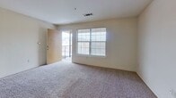 This single-floor residence offers a well-organized layout across two bedrooms and two bathrooms. The galley-style kitchen is a functional highlight, featuring warm honey-toned cabinetry extending from floor to ceiling, granite-look countertops, white appliances including a coil-top range, built-in microwave, refrigerator, and dishwasher, all set atop neutral ceramic tile flooring. The kitchen opens toward the living area, which is finished with plush carpeting and provides access to an outdoor balcony through a sliding glass door framed by a large window that brings in natural light.

Both bedrooms are carpeted and offer a comfortable sense of space, with the primary bedroom featuring a double-door closet for ample storage. The second bedroom also includes a window allowing natural light. Both bathrooms are consistent in design, each featuring tile flooring, a tub-shower combination with dark tile surround, a wood-framed vanity with granite-look countertops, a large mirror, and modern light fixtures. The overall aesthetic is clean, neutral, and move-in ready.