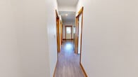 Located at 1200 Billy Frank Jr St in Bellingham, WA, this unit offers four bedrooms and one bathroom across a single floor. The interior features consistent light wood-look flooring and crisp white walls accented by warm wood-toned baseboards throughout. The kitchen is outfitted with light maple cabinetry, white countertops, and a full suite of stainless steel appliances including a refrigerator, electric range, microwave, and dishwasher, all illuminated by recessed lighting. The bedrooms are well-proportioned, with several featuring individual windows that bring in natural light and views of the surrounding neighborhood. Multiple bedrooms include built-in closets with hanging rods, providing practical storage. One bedroom opens to a common area with built-in open shelving, adding functional storage space. The shared bathroom is thoughtfully designed with a light wood vanity, white countertop, a full tub-shower combination, and recessed lighting, maintaining the clean aesthetic found throughout the unit. The entry area features a windowed door that allows additional natural light into the space. Overall, the unit presents a clean, modern, and functional design well-suited for shared occupancy.