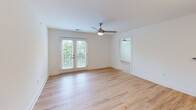 Located at 803 Holliday Dr in Greensboro, NC, this 2-bedroom, 2-bathroom unit offers a thoughtfully designed single-floor layout with modern finishes throughout. Light wood-tone flooring flows consistently across the entire space, creating a bright, cohesive feel.

The kitchen is a standout feature, equipped with crisp white shaker cabinets, granite countertops, stainless steel appliances including a refrigerator, range, and microwave, and a peninsula with a built-in sink and pendant lighting. A distinctive sliding barn door adds a stylish touch near the kitchen entry.

The open living room is bathed in natural light from large French doors that lead to an outdoor view of lush greenery, complemented by a ceiling fan overhead. Both bedrooms are well-lit with multiple windows framing tree-lined views, and each includes its own ceiling fan. The primary bedroom offers generous proportions with an en-suite bathroom featuring a granite vanity and a walk-in shower. The second bathroom is equally well-finished with clean, modern fixtures.

Throughout the unit, white walls, recessed lighting, and clean architectural lines contribute to a bright, contemporary ambiance that feels open and inviting despite its compact and efficient footprint.