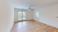 Located at 803 Holliday Dr in Greensboro, NC, this 2-bedroom, 2-bathroom unit offers a thoughtfully designed single-floor layout with modern finishes throughout. Light wood-tone flooring flows consistently across the entire space, creating a bright, cohesive feel.

The kitchen is a standout feature, equipped with crisp white shaker cabinets, granite countertops, stainless steel appliances including a refrigerator, range, and microwave, and a peninsula with a built-in sink and pendant lighting. A distinctive sliding barn door adds a stylish touch near the kitchen entry.

The open living room is bathed in natural light from large French doors that lead to an outdoor view of lush greenery, complemented by a ceiling fan overhead. Both bedrooms are well-lit with multiple windows framing tree-lined views, and each includes its own ceiling fan. The primary bedroom offers generous proportions with an en-suite bathroom featuring a granite vanity and a walk-in shower. The second bathroom is equally well-finished with clean, modern fixtures.

Throughout the unit, white walls, recessed lighting, and clean architectural lines contribute to a bright, contemporary ambiance that feels open and inviting despite its compact and efficient footprint.
