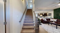 Located in College Station, TX, this two-story, 5-bedroom, 5-bathroom home offers a well-designed layout spread across two generously sized floors. The main level features an open-concept kitchen and living area. The kitchen is appointed with dark espresso cabinetry, granite countertops, stainless steel appliances, and a peninsula bar with pendant lighting — ideal for casual dining and entertaining. Wood-look flooring runs throughout the kitchen and living areas, while the living room boasts a striking green botanical accent wall, ceiling fan, and large windows that flood the space with natural light. Each of the five bedrooms includes its own dedicated closet and private bathroom, offering exceptional privacy. Bedrooms feature plush carpeting and natural light from well-placed windows. The bathrooms are finished with granite-topped vanities, tile flooring, and tub-shower combinations. A standout feature of this home is the private outdoor balcony, which offers serene views of a community pond framed by lush greenery and mature trees. The two-floor layout provides functional separation between living and sleeping spaces, making this home well-suited for shared or family living in the heart of Aggieland.