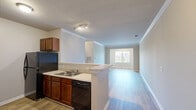 Located at 536 St Thomas St in Rock Hill, SC, this single-floor residence offers a well-organized layout with three bedrooms, two full bathrooms, and a thoughtfully designed mix of living spaces. The kitchen and living room flow together in an open-concept arrangement, where the kitchen features warm wood-toned cabinetry, light countertops, a double-basin sink, and black appliances including a range, dishwasher, refrigerator, and microwave. A peninsula counter with crown molding detail and track lighting adds a practical yet polished touch, complemented by wood-look flooring throughout the main areas. The living room is bright and open, with neutral walls, clean white baseboards, and crown molding accents. The generously sized primary bedroom benefits from natural light through a wide window with blinds, plush carpet flooring, and a ceiling fan. The additional bedrooms also feature carpet, ceiling fans, and closets for ample storage. Both bathrooms are equipped with tub-shower combinations. A dedicated laundry room with wire shelving and utility hookups adds everyday convenience. Neutral tones and consistent finishes throughout give the space a cohesive, move-in ready feel.