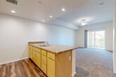 Located in Yucaipa, CA, this single-floor, two-bedroom, two-bathroom residence offers a well-designed layout with a practical and comfortable flow throughout. The open-concept kitchen is a central highlight, featuring warm honey-toned cabinetry, granite-style laminate countertops, a peninsula with a double-basin sink, and recessed lighting overhead. White appliances — including a refrigerator, range, and microwave — are neatly integrated into the kitchen. Wood-look flooring runs through the kitchen area, while plush carpeting covers the living room and both bedrooms, adding warmth and comfort underfoot. The living room is bright and airy, illuminated by recessed lighting and a ceiling fan, with a sliding glass door that opens to a private balcony offering outdoor views. Both bedrooms are generously proportioned with large windows fitted with vertical blinds that invite natural light. The primary bedroom includes its own walk-in closet with dual hanging rods. The bathrooms are finished with matching cabinetry and granite-style countertops, complemented by wood-look flooring. Additional features include a dedicated laundry area, a hallway connecting the main spaces, and ample closet storage throughout the home.