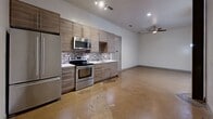 This contemporary 2-bedroom, 2-bathroom residence offers a well-designed single-floor layout with a clean, modern aesthetic throughout. Polished concrete floors flow seamlessly across the open living area and into the kitchen, lending an industrial-chic quality to the space.

The kitchen is a functional highlight, featuring flat-front wood-toned cabinetry, stainless steel appliances including a refrigerator, range, and built-in microwave, along with a striking mosaic tile backsplash and white countertops. Track lighting illuminates the space, while a ceiling fan in the adjacent living area provides additional comfort.

A central hallway connects the bedrooms, bathrooms, and closets with efficient flow. Both bedrooms are bright and well-proportioned, with the generously sized primary bedroom benefiting from natural light through a window with blinds. Each bedroom is accompanied by its own closet for ample storage.

The two bathrooms echo the modern design language with large-format light tile flooring, floating vanities topped with white basins, oval mirrors, and contemporary light fixtures. One bathroom features a full soaking tub with tile surround, while the other offers a walk-in shower. The clean, neutral palette throughout creates a cohesive and move-in ready environment.