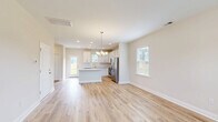 This contemporary 1,350 square foot home in Navassa, NC offers a thoughtful layout across two floors. The ground floor spans 570 sq ft, while the upper level provides 790 sq ft of living space. The home features three bedrooms, including a generous 180 sq ft primary suite, and three full bathrooms.

The interior is characterized by an open-concept design, showcasing light-filled rooms with hardwood flooring throughout. Large windows with white blinds allow ample natural light, complementing the neutral wall tones. The kitchen boasts white cabinetry, stainless steel appliances, and a functional island, ideal for meal preparation and casual dining.

Each bedroom offers spacious comfort, with the primary bedroom featuring an en-suite bathroom. The bathrooms are appointed with modern fixtures, including a sleek vanity and a tub-shower combination. Ample closet space, including wire shelving, provides storage solutions throughout the home.

Additional amenities include a single-car garage with a modern garage door system and recessed lighting. The property is enhanced by a fenced backyard, offering privacy and outdoor living potential. Located at 304 Bedstone Dr, this home combines modern aesthetics with practical living spaces, making it an attractive option for various lifestyle needs.