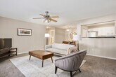 This single-floor, 2-bedroom, 3-bathroom residence features a thoughtfully organized layout designed for comfortable everyday living. A carpeted hallway with wood-look flooring at the entry connects the main living areas, setting a warm and cohesive tone throughout. The living room is bright and inviting, highlighted by a ceiling fan, plush carpet, and French doors that allow generous natural light to filter in. Adjacent to the living room, the dining area accommodates a full dining set and features a pendant light overhead. The galley-style kitchen is well-equipped with white cabinetry, dark countertops, a double stainless steel sink, and matching white appliances, including a range, dishwasher, and microwave. Wood-look flooring runs throughout the kitchen. The primary bedroom is generously proportioned, featuring dual windows that bring in natural light, soft carpet, and a ceiling fan. Additional bedrooms offer comfortable sizing with carpet and easy access to the hallways. Three bathrooms are finished consistently with dark countertops, white cabinetry, and wood-look flooring. A dedicated in-unit laundry room with wire shelving and full-size washer and dryer hookups adds significant practicality to the home.