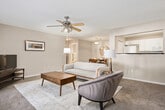 This single-floor, 2-bedroom, 3-bathroom residence features a thoughtfully organized layout designed for comfortable everyday living. A carpeted hallway with wood-look flooring at the entry connects the main living areas, setting a warm and cohesive tone throughout. The living room is bright and inviting, highlighted by a ceiling fan, plush carpet, and French doors that allow generous natural light to filter in. Adjacent to the living room, the dining area accommodates a full dining set and features a pendant light overhead. The galley-style kitchen is well-equipped with white cabinetry, dark countertops, a double stainless steel sink, and matching white appliances, including a range, dishwasher, and microwave. Wood-look flooring runs throughout the kitchen. The primary bedroom is generously proportioned, featuring dual windows that bring in natural light, soft carpet, and a ceiling fan. Additional bedrooms offer comfortable sizing with carpet and easy access to the hallways. Three bathrooms are finished consistently with dark countertops, white cabinetry, and wood-look flooring. A dedicated in-unit laundry room with wire shelving and full-size washer and dryer hookups adds significant practicality to the home.