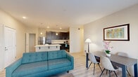 This single-floor, 2-bedroom, 2-bathroom residence offers a thoughtfully organized layout that maximizes functionality within a compact footprint. The open-concept living and dining area serves as the heart of the unit, featuring light wood-style flooring, neutral wall tones, and large windows that allow generous natural light to fill the space. A glass-paneled exterior door in the dining area provides additional brightness and outdoor access.

The kitchen is well-appointed with dark espresso cabinetry extending to the ceiling, crisp white countertops, a peninsula with an integrated sink and pendant lighting, and a full suite of stainless steel appliances including a refrigerator, range, and microwave. Light wood-style flooring continues seamlessly from the kitchen into the living areas.

Both bedrooms are carpeted and comfortably scaled, with the primary bedroom offering a window with outdoor views. A closet with sliding doors and wire shelving provides practical storage. Two full bathrooms serve the unit, and a dedicated in-unit laundry area houses a full-sized washer and dryer with overhead shelving. The overall ambiance is clean, modern, and cohesive throughout.
