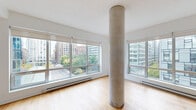Located in the heart of downtown Montréal on Rue de Bleury, this well-appointed 2-bedroom, 1-bathroom residence offers a thoughtfully designed single-level layout. The spacious living room is a standout feature, anchored by an exposed concrete structural column that adds an industrial-modern character. Large floor-to-ceiling windows on multiple sides flood the space with natural light and frame impressive views of the surrounding cityscape, including mature trees and Montréal's vibrant urban skyline. Warm hardwood flooring flows consistently throughout the living areas and bedrooms, contributing to a cohesive and inviting aesthetic.

The primary bedroom is generously sized, featuring a built-in closet and large window with city views. The second bedroom also benefits from hardwood floors, a closet, and ample natural light. Both rooms maintain the clean, neutral palette found throughout the residence.

The bathroom has been renovated to a high standard, showcasing a warm wood-toned vanity with a white quartz countertop, a large frameless mirror with modern bar lighting, a glass-enclosed shower with marble-style tile, and distinctive hexagonal floor tiles. A hallway connecting the rooms provides additional storage and smooth flow between spaces. The overall ambiance is bright, modern, and urban.