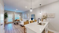 Located at 800 NW Ward Rd in Lee's Summit, MO, this thoughtfully designed 2-bedroom residence offers a cohesive, contemporary aesthetic throughout its single-floor layout. The open-concept kitchen and living area serves as the heart of the home, where light wood-look flooring, recessed lighting, and globe pendant lights create a warm, modern atmosphere. The kitchen is outfitted with white flat-front cabinetry extending to the ceiling, a white quartz waterfall island with a matte black faucet and undermount sink, stainless steel appliances, and a subway tile backsplash — combining both style and functionality. The kitchen flows seamlessly into the living room, which is brightened by large windows and a glass-paned exterior door that fills the space with natural light. The primary bedroom is generously proportioned, featuring plush carpet flooring, a ceiling fan, soft neutral-toned walls, and access to a dedicated walk-in closet complete with wire shelving and hanging rods. A second bedroom provides additional flexible living space. Throughout the residence, a calm, neutral color palette and clean architectural lines contribute to a cohesive and inviting ambiance, making this a well-appointed home in a convenient Missouri location.