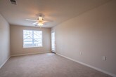 This single-floor unit at 14332 Deloice Crescent in Newport News, Virginia offers a practical and well-organized layout. The entry foyer transitions from tile flooring into a generously sized living area finished with neutral-toned carpet and a ceiling fan with light fixture overhead, creating a comfortable and airy atmosphere. A window allows natural light to fill the space.

The kitchen is efficiently designed and features rich, medium-toned wood cabinetry extending to the upper walls, providing ample storage. Dark granite-style countertops complement the suite of black appliances, including an electric range, over-range microwave, and refrigerator. Stone-look tile flooring runs throughout the kitchen, offering durability and easy maintenance.

The bedroom is spacious and carpeted, with neutral walls, a closet with built-in shelving, and a window with blinds that brings in natural light. The layout offers a comfortable and functional personal retreat.

The bathroom is clean and straightforward, featuring stone-look tile flooring, a white toilet, a wall-mounted grab bar, a dark wood vanity with a white countertop, and a mirror with towel bar above. The neutral beige walls keep the space feeling bright and simple throughout.