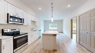 This well-designed one-bedroom, one-bathroom unit in Waco, TX offers a clean, modern aesthetic with a thoughtful open-concept layout. Light wood-style flooring flows continuously throughout the entire space, creating a cohesive and bright atmosphere.

The kitchen and living area form a unified open space at the heart of the unit. The kitchen is outfitted with crisp white shaker-style cabinetry, a full suite of stainless steel appliances including a range, microwave, dishwasher, and refrigerator, and a central island with a light countertop illuminated by a sleek pendant light. A window at the far end of the living area brings in natural light and offers views of the surrounding greenery.

The bedroom is a well-proportioned private retreat featuring a ceiling fan, a window with outdoor views, and direct access to an exterior door. The room is finished in neutral warm tones with ample wall space for flexible furniture arrangements. Adjacent to the bedroom is a walk-in closet equipped with built-in shelving and hanging rods for organized storage.

The bathroom is clean and functional, featuring a full tub-shower combo, a white vanity with storage cabinetry above, and consistent wood-style flooring. Recessed lighting keeps the space feeling bright and open. Overall, the unit presents a fresh, move-in-ready environment with modern finishes throughout.