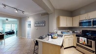 This single-floor residence offers a thoughtfully designed layout that balances comfort and functionality across its key living spaces. The kitchen is equipped with stainless steel appliances, including a range, microwave, and refrigerator, complemented by light wood cabinetry, granite-style countertops, and a peninsula with bar seating — ideal for casual dining or entertaining. Tile flooring runs throughout the kitchen and connects seamlessly to the surrounding areas.

The living room is a welcoming, light-filled space featuring crown molding, a ceiling fan, and large windows dressed with teal curtains that invite natural light. The room provides a comfortable and open atmosphere suited for relaxing or gathering.

Each bedroom is carpeted for warmth and comfort, with ample space for a bed and a dedicated workspace. Walk-in closets offer generous storage, while ceiling fans add to the livability of the rooms. The bedrooms are finished in neutral tones that create a calm, functional environment.

The bathrooms are clean and practical, each featuring a walk-in shower with glass doors, tile flooring, a single-sink vanity with light wood cabinetry, and a large framed mirror. The overall palette throughout the residence is neutral and cohesive, creating a calm and move-in-ready atmosphere.