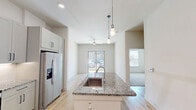 Located at 3550 N A W Grimes Blvd in Round Rock, TX, this thoughtfully designed one-bedroom, one-bathroom residence offers a clean, modern aesthetic across a single floor. The open kitchen serves as the heart of the home, showcasing granite countertops, a peninsula with an undermount sink, stylish pendant lighting, and a full suite of stainless steel appliances including a refrigerator with ice maker, range, microwave, and dishwasher. Gray shaker-style cabinetry with sleek black hardware and a white tile backsplash complete the contemporary look, while light wood-style flooring flows throughout the main living and kitchen areas. The bedroom is a comfortable, carpeted retreat featuring neutral tones, bright natural light from a large window with blinds, and direct access to a dedicated closet. The full bathroom impresses with a wide granite-topped vanity, white cabinetry with black hardware, a large wall mirror, recessed lighting, and a tub-shower combination. The space also benefits from outdoor access, with a grassy patio area visible from the living space, adding a welcoming touch of greenery. Overall, this residence combines practical functionality with modern finishes for a polished, move-in-ready feel.