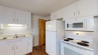 Located at 1587 Regent Ave in Springfield, Ohio, this multi-floor property spans three levels and offers a straightforward, functional layout throughout. The main level features warm hardwood flooring that extends through the kitchen and dining area. The kitchen is equipped with white cabinetry offering ample storage, a full-size refrigerator, electric range, over-the-range microwave, and a single-basin sink. A chandelier illuminates the adjacent dining area, which benefits from multiple windows that bring in natural light. The main entry area is carpeted and includes a staircase connecting the floors, with a front door accented by a decorative diamond-shaped window.

The upper level continues with neutral-toned carpet throughout the bedrooms, each featuring natural light from windows with blinds and clean white walls. A full bathroom on this level includes a tub/shower combination, toilet, and vanity with wood cabinetry, complemented by a window for ventilation and light.

The lower level consists of an unfinished basement with painted concrete block walls, a sealed floor, and exposed ceiling joists, providing practical utility and storage space. Overall, the property presents a clean, functional environment with consistent neutral finishes throughout.