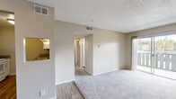 Located in Escondido, CA, this two-bedroom, one-bathroom residence offers a practical and well-organized single-floor layout. The galley-style kitchen is thoughtfully designed with white cabinetry, granite-look countertops, a mosaic tile backsplash, and wood-look vinyl plank flooring, providing an efficient workspace for cooking and meal preparation. A pass-through window connects the kitchen to the living area, enhancing the open feel between spaces. The combined kitchen and living room area serves as the central hub of the home, with plush carpet in the living zone and a textured ceiling overhead. Both bedrooms are carpeted for comfort and feature ceiling fans with light fixtures, vertical blind-covered windows that allow natural light, and neutral-toned walls. The primary bedroom includes a sliding double-door closet for ample storage. The bathroom is clean and functional, featuring a tub-shower combination, a white vanity with granite-look countertop, and wood-look flooring that ties cohesively with the rest of the home. A hallway connects the main living spaces to the bedrooms and bathroom, completing the efficient layout of this Escondido residence.