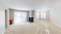 This single-floor residence offers a well-organized layout designed for comfortable everyday living. The living area is generously sized, featuring neutral-toned carpet, a ceiling fan, and a corner fireplace with a tiled hearth as a focal point. Large sliding glass doors with vertical blinds fill the space with natural light and provide outdoor access, while additional windows further brighten the room.

The galley-style kitchen is efficiently arranged with warm oak cabinetry above and below, light-toned countertops, a double stainless steel sink, and white appliances including a stovetop range and microwave. A pass-through counter connects the kitchen to the main living space, enhancing an open feel. Adjacent to the kitchen is a closeted storage area, adding practical utility.

The two bedrooms are carpeted and finished with neutral gray walls and white baseboards. Each features windows with blinds that allow natural light while maintaining privacy. One bedroom includes a walk-in closet with bifold doors and direct access to a private bathroom equipped with a single-sink vanity, wood cabinetry, a lighted mirror, and chrome fixtures. A second full bathroom features a tub-shower combination with white tile surround, a vanity, and neutral finishes throughout.