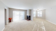 This single-floor residence offers a well-organized layout designed for comfortable everyday living. The living area is generously sized, featuring neutral-toned carpet, a ceiling fan, and a corner fireplace with a tiled hearth as a focal point. Large sliding glass doors with vertical blinds fill the space with natural light and provide outdoor access, while additional windows further brighten the room.

The galley-style kitchen is efficiently arranged with warm oak cabinetry above and below, light-toned countertops, a double stainless steel sink, and white appliances including a stovetop range and microwave. A pass-through counter connects the kitchen to the main living space, enhancing an open feel. Adjacent to the kitchen is a closeted storage area, adding practical utility.

The two bedrooms are carpeted and finished with neutral gray walls and white baseboards. Each features windows with blinds that allow natural light while maintaining privacy. One bedroom includes a walk-in closet with bifold doors and direct access to a private bathroom equipped with a single-sink vanity, wood cabinetry, a lighted mirror, and chrome fixtures. A second full bathroom features a tub-shower combination with white tile surround, a vanity, and neutral finishes throughout.
