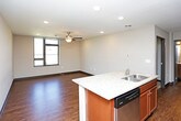 This two-floor residence offers a thoughtfully designed layout with a blend of practical finishes and comfortable living spaces throughout. The kitchen is a standout area, equipped with stainless steel appliances including a refrigerator, range, and built-in microwave, complemented by warm wood cabinetry reaching to the ceiling and granite-style countertops with a stainless steel sink. Rich hardwood flooring adds a polished look to this culinary space. The bedrooms are generously proportioned, featuring plush carpeting, ceiling fans with integrated lighting, and large windows that invite natural light and outdoor views. Dark-trimmed doorways and dark baseboards create a clean contrast against neutral-toned walls throughout. Walk-in closets with wire shelving systems provide ample storage. The bathrooms are well-finished, showcasing rich dark wood vanities with white countertops, large mirrors with overhead vanity lighting, and brushed nickel hardware accents. One bathroom includes a full soaking tub and shower combination with clean white surround. Textured ceilings add subtle dimension, while the overall design maintains a cohesive, modern-casual aesthetic across both floors.