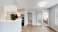 Located at 12801 Roydon Dr in Houston, TX, this 2-bedroom, 2-bathroom single-story home offers a well-organized layout that makes efficient use of its space. The living room is a standout, featuring warm wood-look flooring, soft gray walls, and a striking white stone corner fireplace flanked by windows that invite natural light. The kitchen is outfitted with white cabinetry, light countertops, a subway tile backsplash, and black appliances including a refrigerator, range, dishwasher, and stainless steel microwave. A breakfast bar provides additional counter space, and the kitchen flows naturally into the dining area. Sliding glass doors lead to a private patio with views of the surrounding courtyard and brick exterior architecture. Both bedrooms are carpeted and finished in the same soft gray palette, with the primary bedroom offering a ceiling fan, a window with natural light, and access to a spacious walk-in closet with wire shelving. The bathrooms are clean and functional, featuring white vanities, light countertops, and well-lit mirrors. Three total closets throughout the home provide ample storage. Textured ceilings run throughout, adding a classic touch to this move-in ready Houston residence.